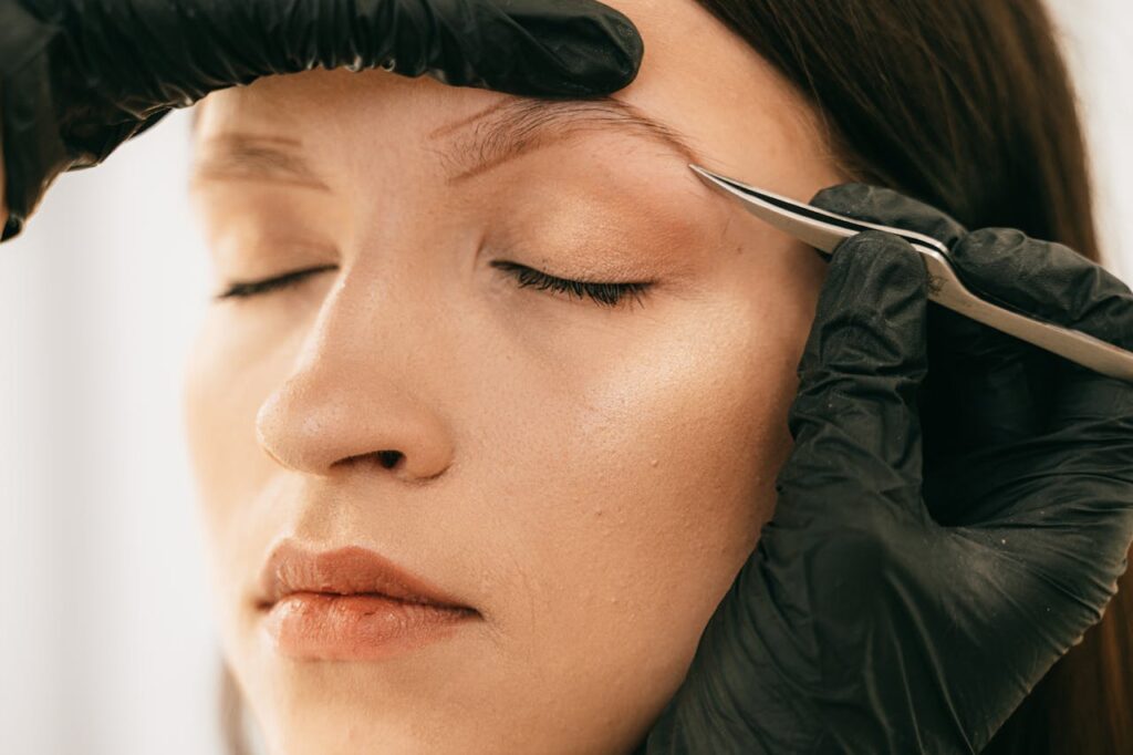 Person Plucking Womans Eyebrow